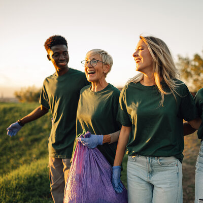 Group of volunteers collecting garbage in park are walking and talking