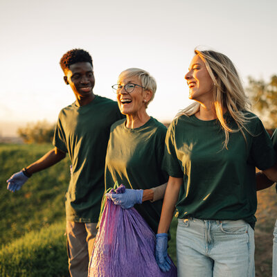 Group of volunteers collecting garbage in park are walking and talking